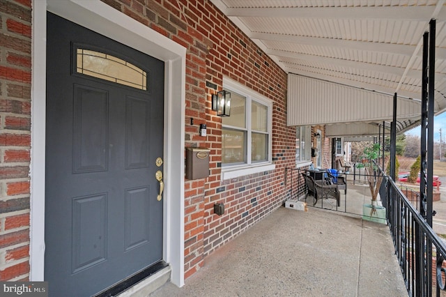property entrance with brick siding and a porch