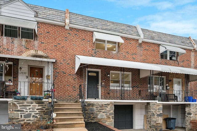 multi unit property with stone siding, an attached garage, and brick siding