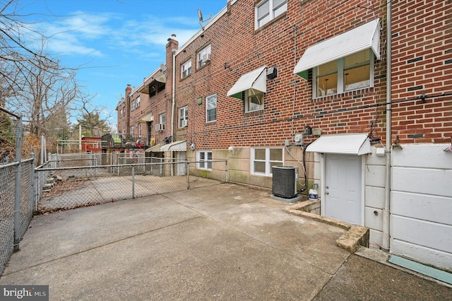 exterior space featuring brick siding, a residential view, central AC unit, and fence