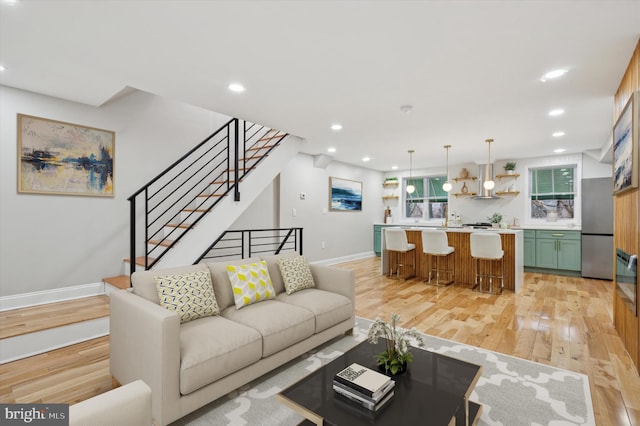 living area featuring light wood-type flooring, baseboards, recessed lighting, and stairway