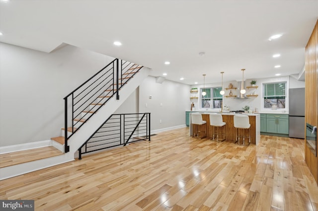 kitchen featuring open shelves, light wood finished floors, light countertops, baseboards, and freestanding refrigerator