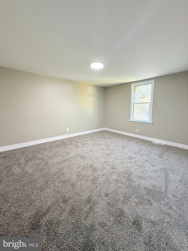 carpeted spare room with visible vents and baseboards