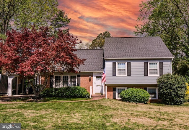 tri-level home featuring a lawn, a shingled roof, and brick siding