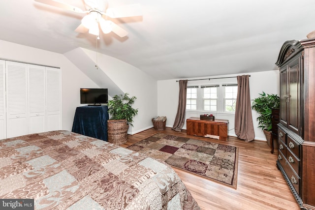 bedroom featuring baseboards, vaulted ceiling, a closet, and light wood-style flooring