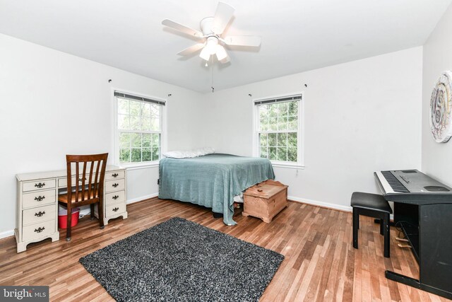 bedroom featuring wood finished floors, a ceiling fan, baseboards, and multiple windows