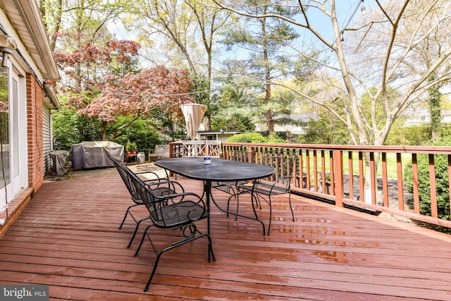 wooden deck with outdoor dining area and a grill