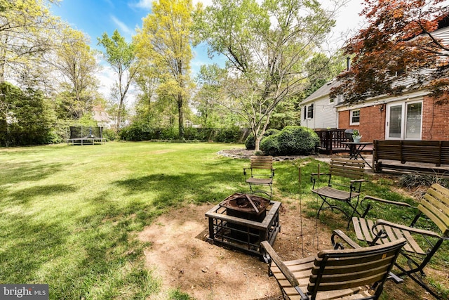 view of yard with a trampoline, an outdoor fire pit, and fence