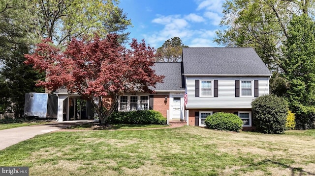 tri-level home featuring concrete driveway, a front lawn, roof with shingles, and brick siding