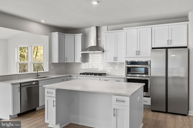 109 Hillsdale Dr, Fredericksburg, VA 22405 - kitchen featuring appliances with stainless steel finishes, wall chimney exhaust hood, a center island, light wood-type flooring, and light stone counters