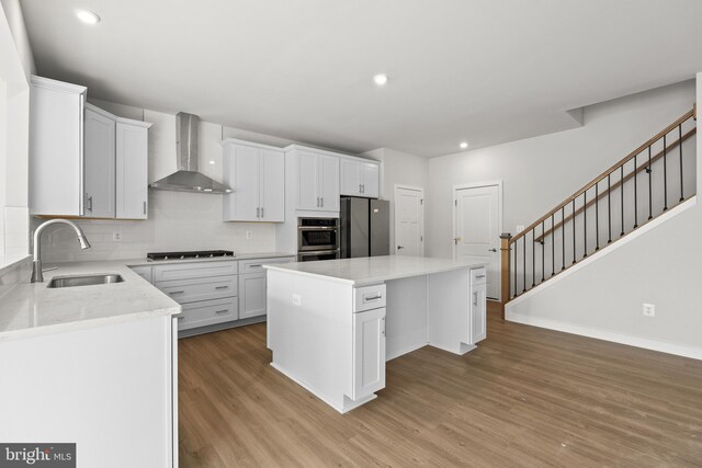 109 Hillsdale Dr, Fredericksburg, VA 22405 - kitchen featuring wall chimney range hood, appliances with stainless steel finishes, light wood-style floors, a center island, and tasteful backsplash