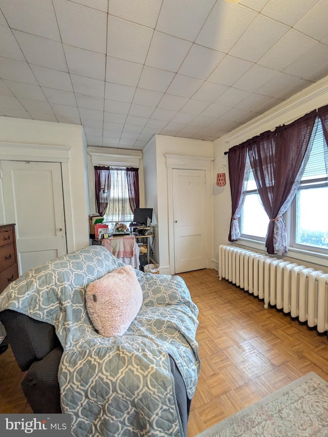 bedroom featuring radiator heating unit and multiple windows