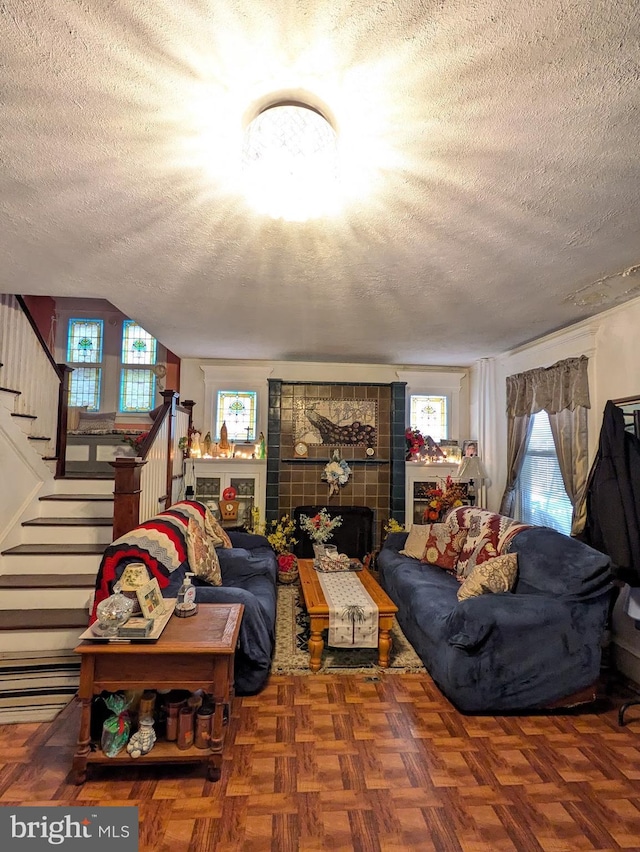 living area with a fireplace, a textured ceiling, and stairs