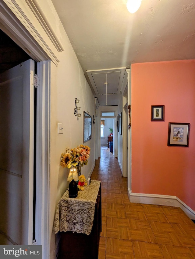 hallway featuring attic access and baseboards
