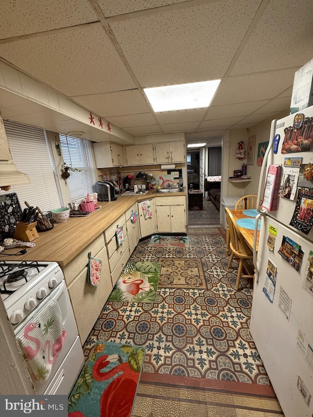 kitchen featuring light countertops, a sink, white appliances, and a paneled ceiling