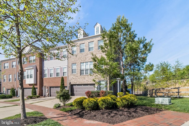 townhome / multi-family property with an attached garage, fence, driveway, and brick siding