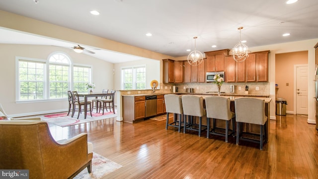 13002 Walkers Ln, Bowie, MD 20721 - kitchen featuring brown cabinets, appliances with stainless steel finishes, dark wood finished floors, a center island, and decorative backsplash
