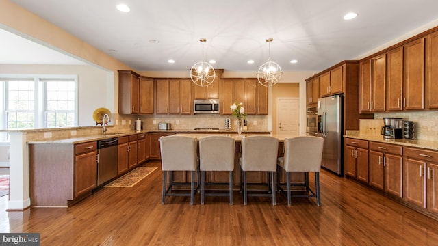 13002 Walkers Ln, Bowie, MD 20721 - kitchen with brown cabinetry, a kitchen bar, tasteful backsplash, a sink, and stainless steel appliances