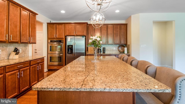 13002 Walkers Ln, Bowie, MD 20721 - kitchen featuring an inviting chandelier, a kitchen breakfast bar, stainless steel appliances, wood finished floors, and backsplash