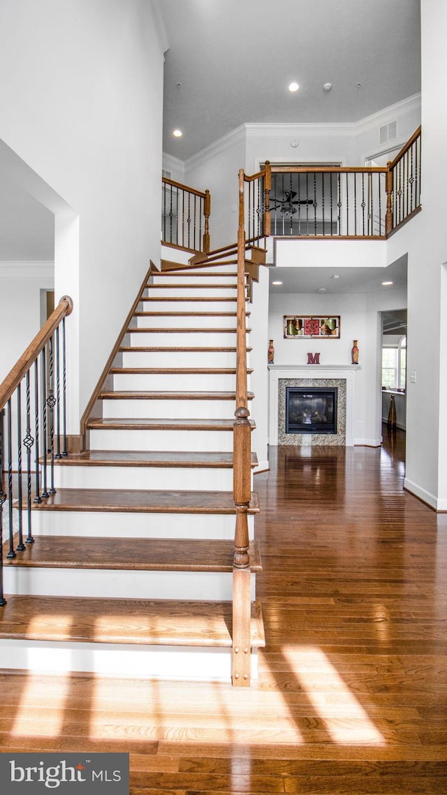 13002 Walkers Ln, Bowie, MD 20721 - staircase featuring a high ceiling, a glass covered fireplace, ornamental molding, and wood finished floors