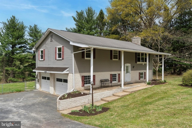 bi-level home with a chimney, fence, a front lawn, driveway, and a garage