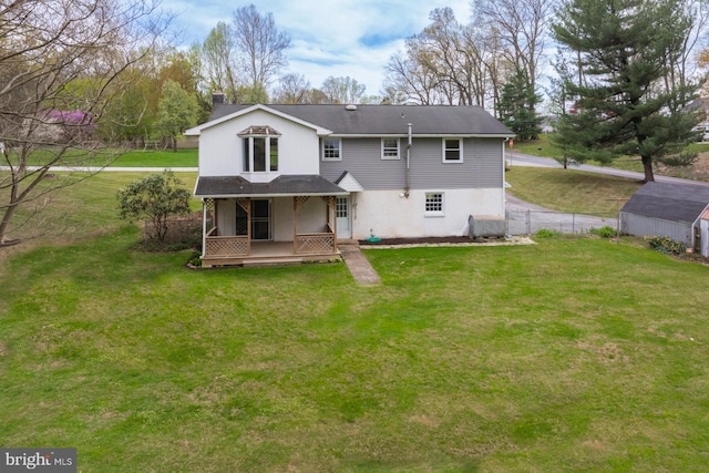 rear view of property with a chimney, fence, an outbuilding, covered porch, and a lawn