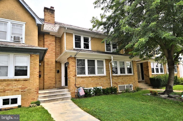 view of front of home with a chimney, brick siding, and a front yard