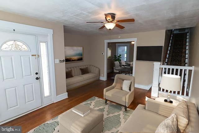 living room with baseboards, a ceiling fan, and wood finished floors