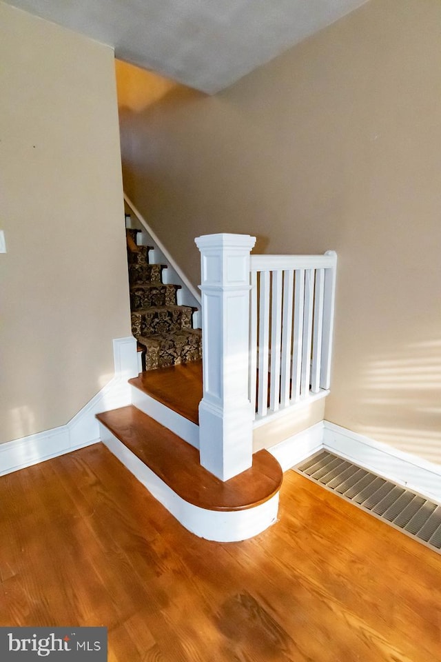 staircase featuring wood finished floors and baseboards