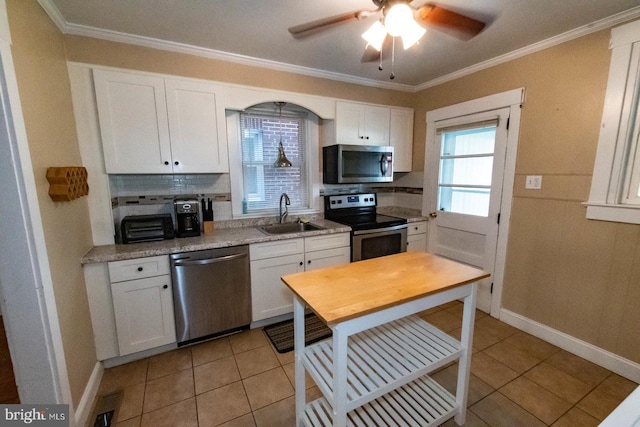 kitchen featuring a ceiling fan, light tile patterned floors, a sink, decorative backsplash, and appliances with stainless steel finishes