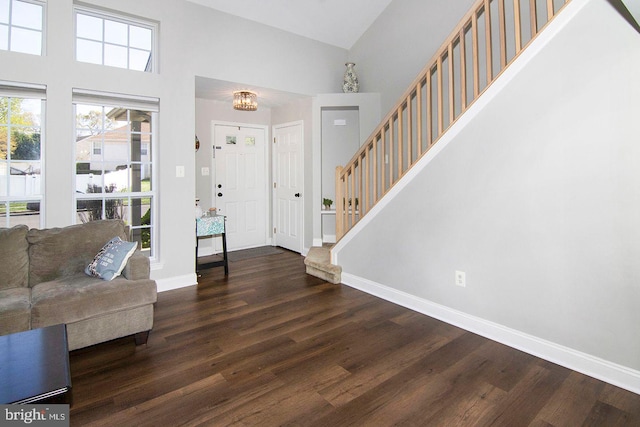 foyer featuring baseboards, a high ceiling, stairs, and wood finished floors