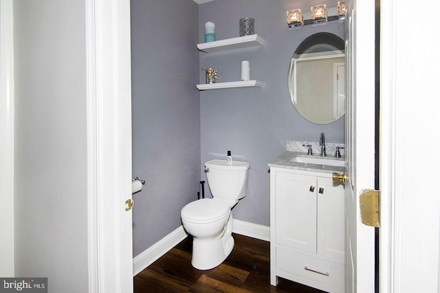 bathroom with baseboards, wood finished floors, toilet, and vanity