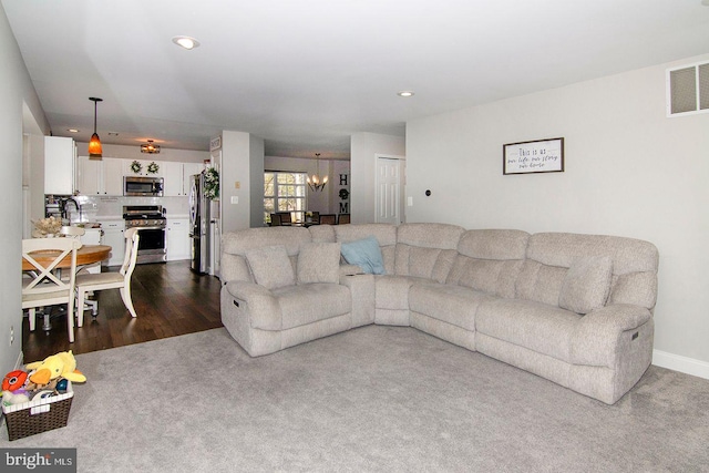 living room with visible vents, recessed lighting, a chandelier, dark carpet, and dark wood-type flooring
