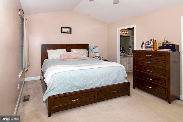 bedroom with visible vents, light carpet, lofted ceiling, and ensuite bath