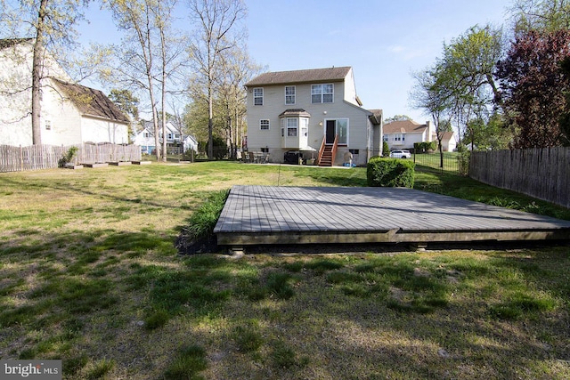rear view of house featuring a fenced backyard, a wooden deck, and a yard