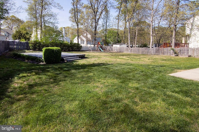 view of yard featuring a fenced backyard and a playground