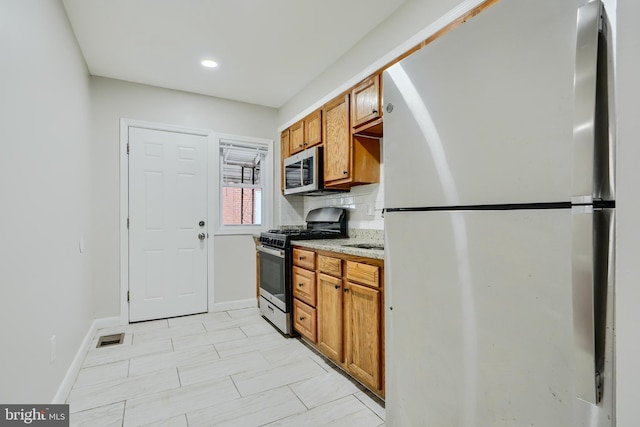 kitchen with appliances with stainless steel finishes, brown cabinets, baseboards, backsplash, and recessed lighting