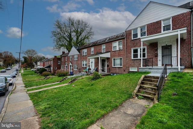 townhome / multi-family property with brick siding, a front lawn, and a residential view
