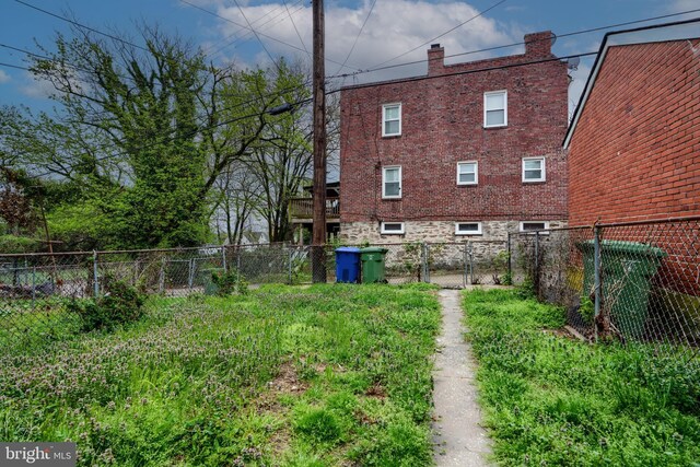 rear view of property with a chimney, brick siding, fence, and a gate