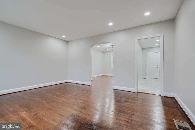 spare room with dark wood-style flooring, recessed lighting, arched walkways, baseboards, and a ceiling fan