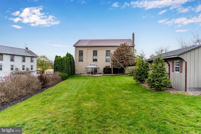 back of property with a lawn and a gazebo