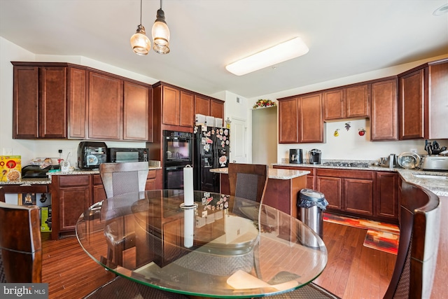 kitchen with black appliances, light stone countertops, dark wood-style floors, and decorative light fixtures