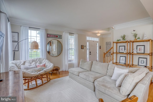 living area featuring wood finished floors, stairs, and ornamental molding