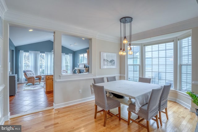 dining area with vaulted ceiling, baseboards, light wood-style floors, and crown molding