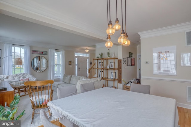 dining area featuring light wood finished floors, visible vents, a wealth of natural light, and crown molding