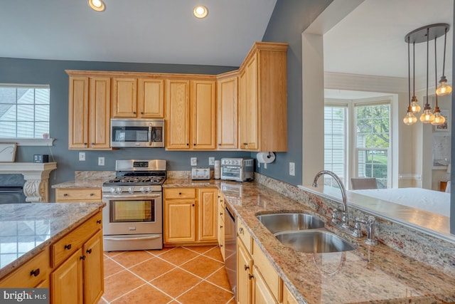 kitchen with a sink, light tile patterned flooring, light brown cabinetry, stainless steel appliances, and decorative light fixtures