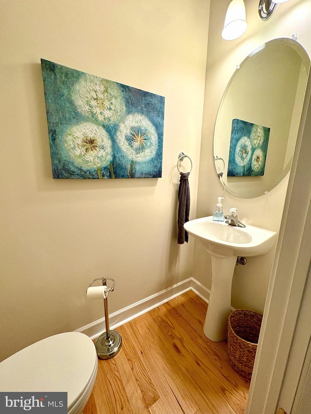 bathroom with baseboards, wood finished floors, and toilet