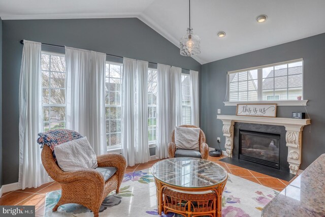 sitting room with a fireplace with flush hearth, plenty of natural light, vaulted ceiling, and tile patterned flooring