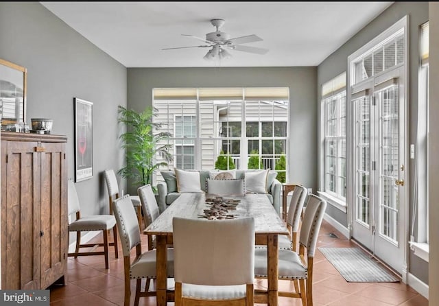 tiled dining area featuring a ceiling fan, baseboards, and a healthy amount of sunlight
