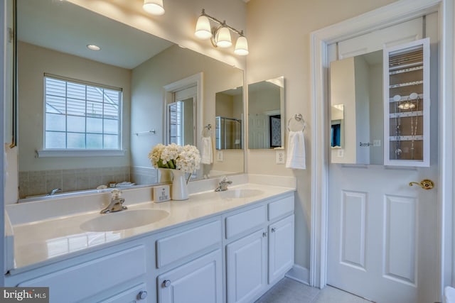 bathroom with double vanity, tile patterned floors, a stall shower, and a sink