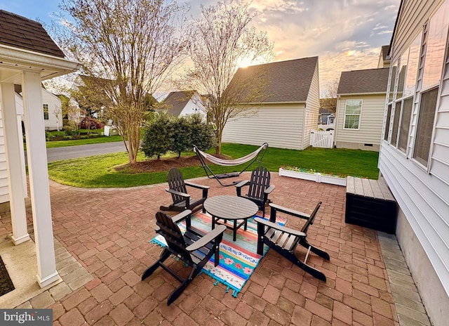 patio terrace at dusk featuring a yard